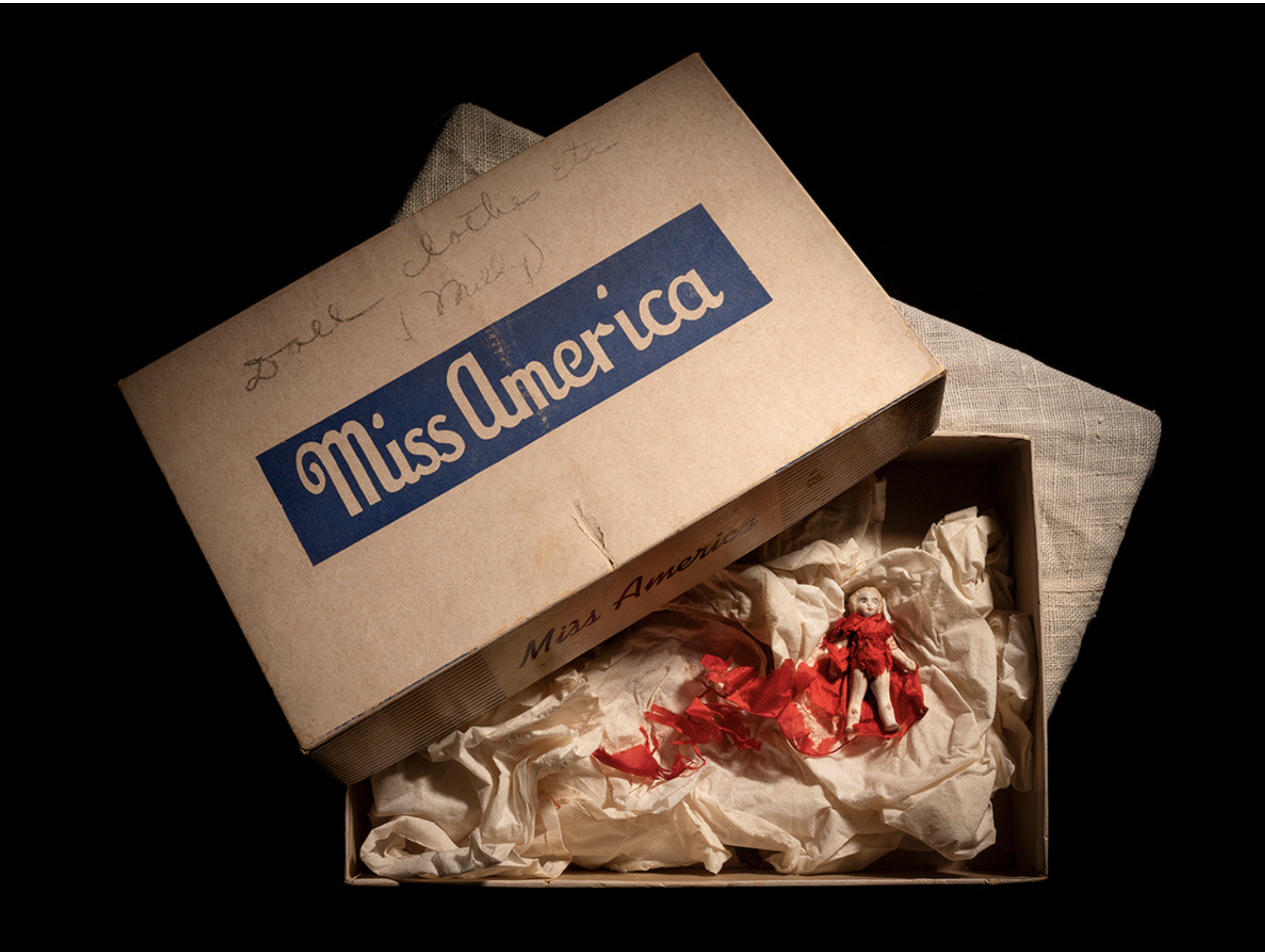 Opened box with a doll inside. Box lid says "Miss America"